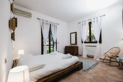 a white bedroom with a large bed and two windows at LuminHouse Mondello Arancia in Mondello
