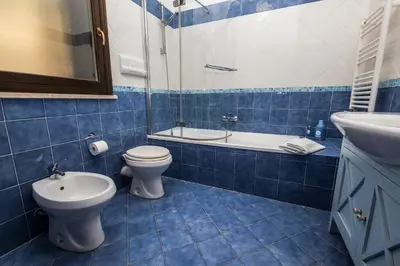 a blue tiled bathroom with a toilet and a sink at LuminHouse Mondello Arancia in Mondello