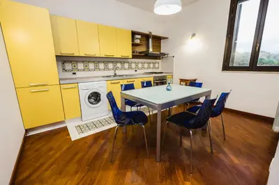 a kitchen with yellow cabinets and a table and chairs at LuminHouse Mondello Limone in Mondello