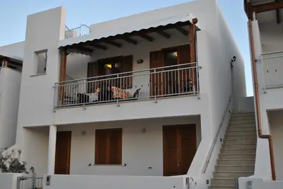 a white house with stairs and a balcony at Casa Frida in San Vito lo Capo