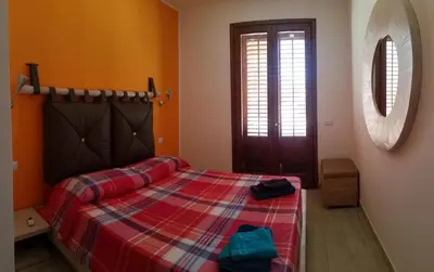 a bedroom with a bed with a plaid blanket at Casa Frida in San Vito lo Capo
