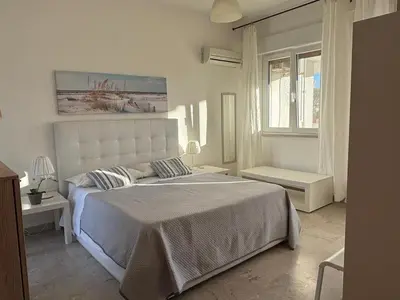 a white bedroom with a large bed and a window at Near the beach in Palermo