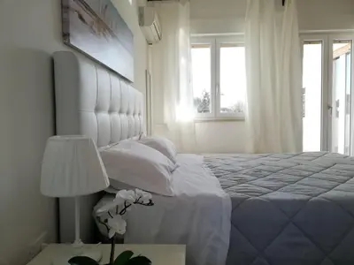 a white bedroom with a large bed and windows at Near the beach in Palermo