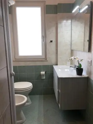 a bathroom with a toilet and a sink and a window at Near the beach in Palermo