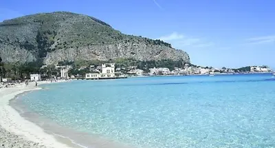 a view of a beach with a mountain in the background at Near the beach in Palermo