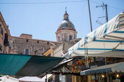 a building with a clock tower in the background of a market at APT Ballarò House - Superior Apartment in Palermo