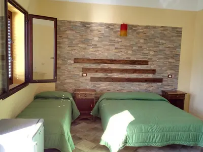 a room with two beds and a brick wall at Agriturismo La Targa in Buonfornello