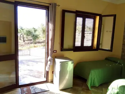 a room with a refrigerator and a sliding glass door at Agriturismo La Targa in Buonfornello