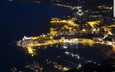 a city at night with boats in the water at Casa Vacanza Brigida in Scopello