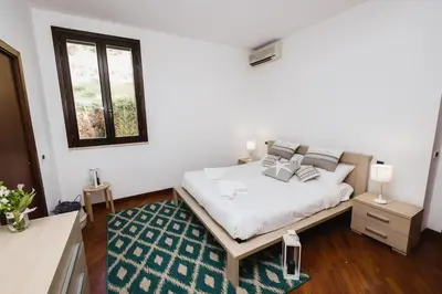 a bedroom with a white bed with a green rug at LuminHouse Villa Mondello in Mondello