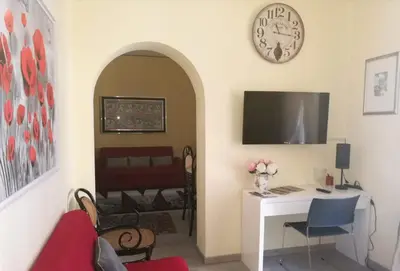 a living room with a desk and a clock on the wall at Pretty house in Palermo