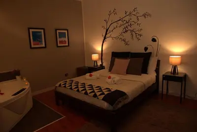 a bedroom with a bed with two lamps and a tree on the wall at SuiteSicily Rooms Palermo in Altavilla Milicia