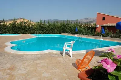 a swimming pool with two chairs and a table at Villa Siragusa con piscina condominiale in Campofelice di Roccella
