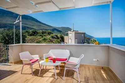 a balcony with white chairs and a table and a view at La Finestra sul Mare dello Zingaro in Scopello