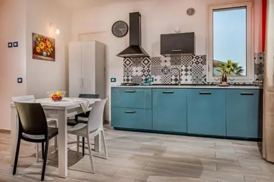 a kitchen with blue cabinets and a table with chairs at La Finestra sul Mare dello Zingaro in Scopello