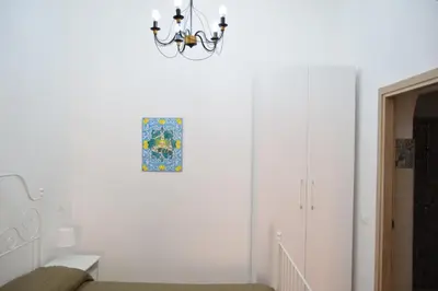 a white hallway with a chandelier and a staircase at Le Volte - Locazione Turistica in Terrasini