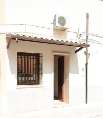 a small white house with a window and a fan at Le Volte - Locazione Turistica in Terrasini