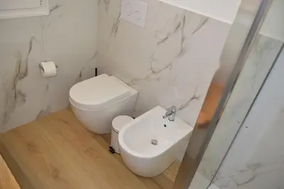 a white bathroom with a toilet and a sink at Caporama in Terrasini