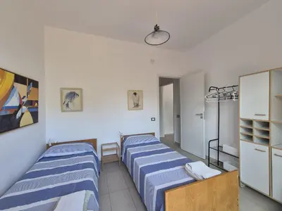 two beds in a room with white walls at Casa in villa vista mare in Palermo