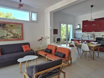 a living room and kitchen with a blue couch and orange chairs at Casa in villa vista mare in Palermo