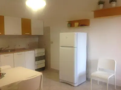 a kitchen with a white refrigerator and a table and chairs at fabrizio e caterina in San Vito lo Capo