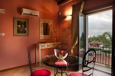 a dining room with a glass table and chairs and a balcony at Il Baglio Della Luna Relais by Le Dhome Sicily in Balestrate