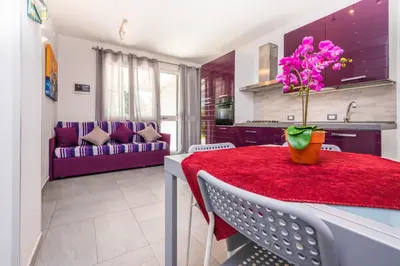 a kitchen and living room with a table with a vase of flowers at Villa Sara in Lascari