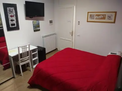 a bedroom with a red bed and a desk and a television at Vado Al Massimo in Palermo