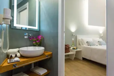 a bathroom with a sink and a bedroom with a bed at Bellaroto Suite & Spa - Charming Boutique Rooms in Palermo