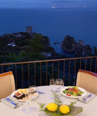 a table with plates of food and wine glasses at Torre Bennistra in Scopello