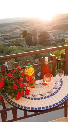 a table with a drink and flowers on a balcony at La casa di Bia in Corleone