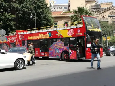 a red double decker bus driving down a street at A Palermo Sono in Palermo