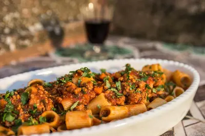 a bowl of pasta with meat and vegetables on a table at Masseria Rossella in Piana degli Albanesi