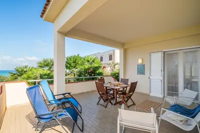 a patio with a table and chairs and the ocean at Villa DellAcqua in Alcamo Marina