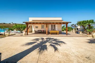 a shadow of a palm tree in front of a house at Villa DellAcqua in Alcamo Marina