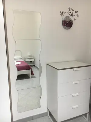 a mirror in a room with a bed and a dresser at La Casetta di Andrea & Vale in Termini Imerese