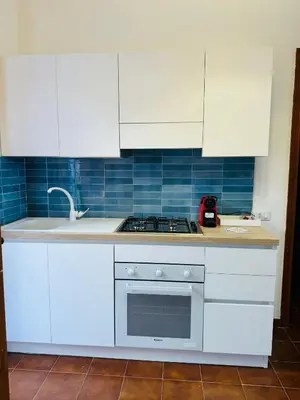 a kitchen with white cabinets and a stove top oven at La maison sul mare in San Vito lo Capo