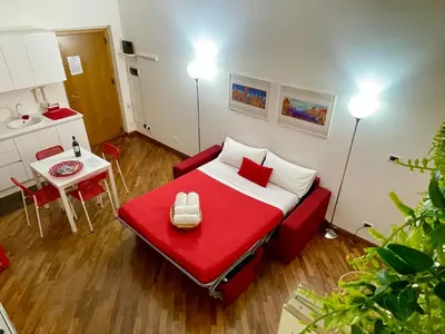 a small room with a red bed and a table at Casa Ina Palermo in Palermo