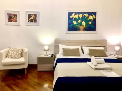 a bedroom with two beds and a chair and a painting at Casa Ina Palermo in Palermo