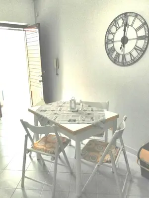 a table with two chairs and a clock on the wall at Il Mulino in San Vito lo Capo