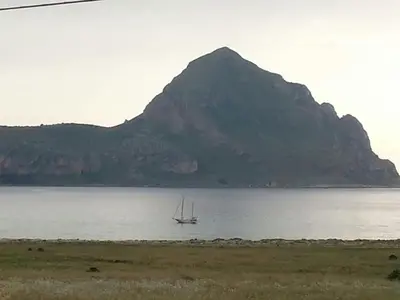 a boat in the water in front of a mountain at Il Mulino in San Vito lo Capo