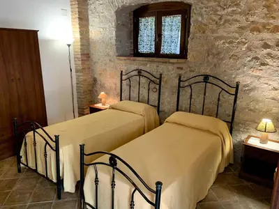 two beds in a bedroom with a stone wall at Agriturismo Sant'Agata in Piana degli Albanesi