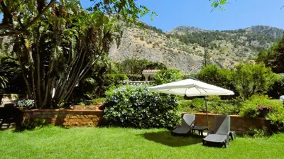 two chairs and an umbrella in the grass at Bouganville Home Mondello in Mondello
