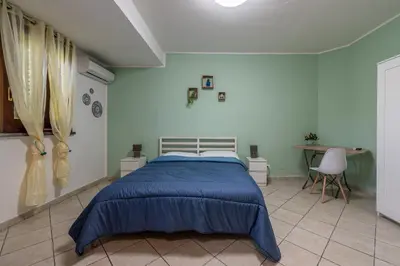 a bedroom with a blue bed and a desk at Bouganville Home Mondello in Mondello