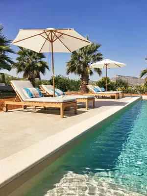 a pool with lounge chairs and umbrellas next to the water at Nômade - Slow Living Lodge in Balestrate