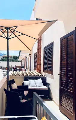 a balcony with a bed and an umbrella at Sicilia Vacation in San Vito lo Capo