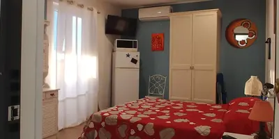 a bedroom with a red bed and a refrigerator at La Rosa dei Venti in Isola delle Femmine