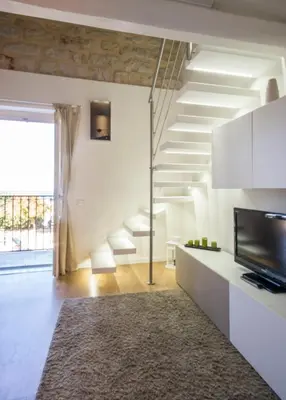 a white living room with a television and a rug at Casa Gelsomino in Palermo