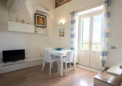a dining room with a white table and chairs and a television at Casa Gelsomino in Palermo