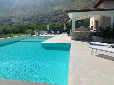 a blue swimming pool with chairs and a house at Villa Cycas Costamante in Castellammare del Golfo